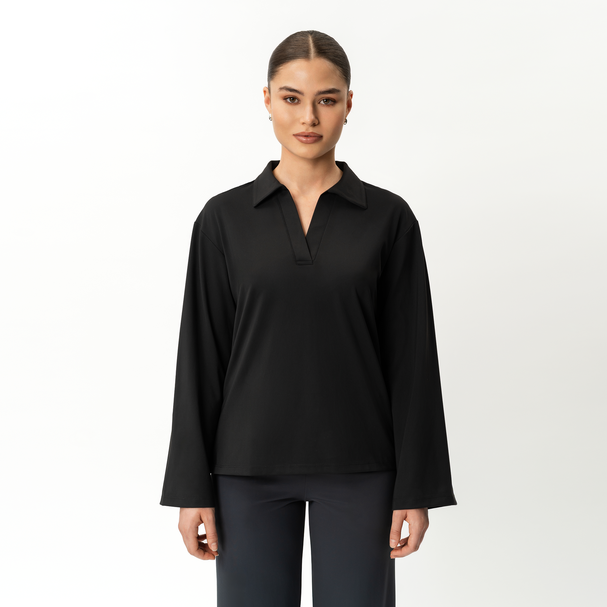 Woman wearing a Ninepine Asana black long-sleeve shirt on a white background