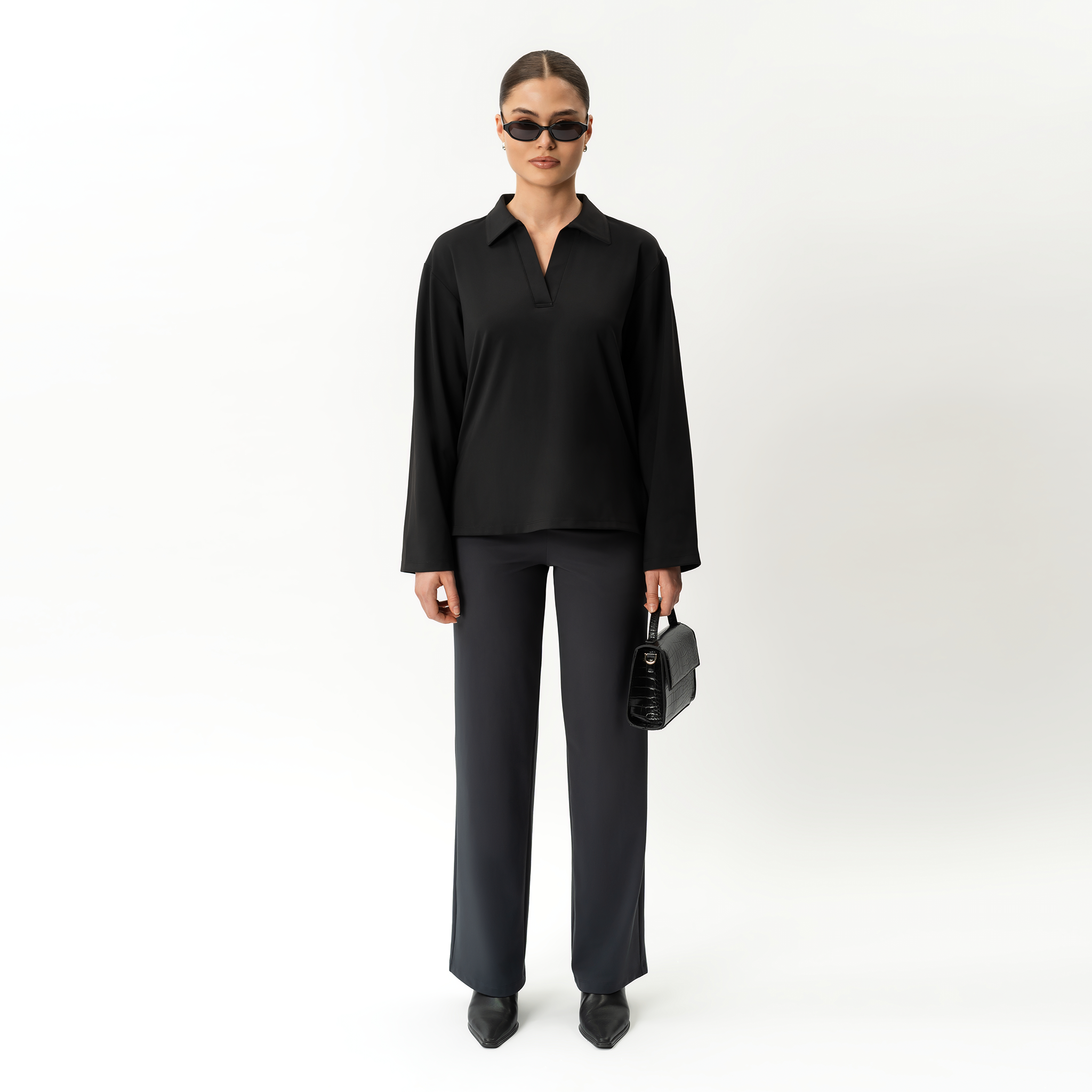 Person wearing Ninepine black outfit with sunglasses and a handbag on a white background