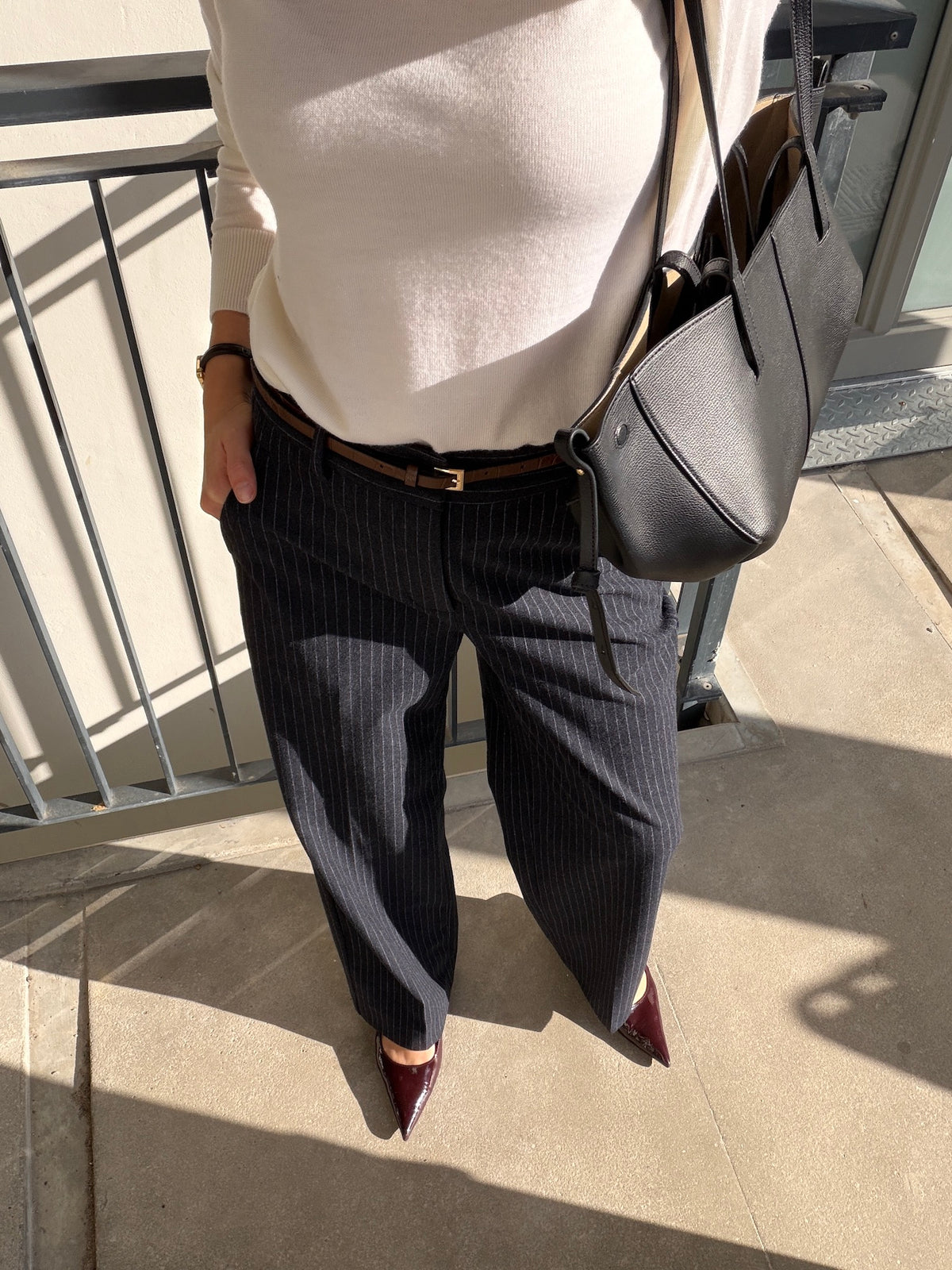 Woman wearing the Ninepine Flannel Daily Pant in navy pinstripe with a cream sweater and leather tote